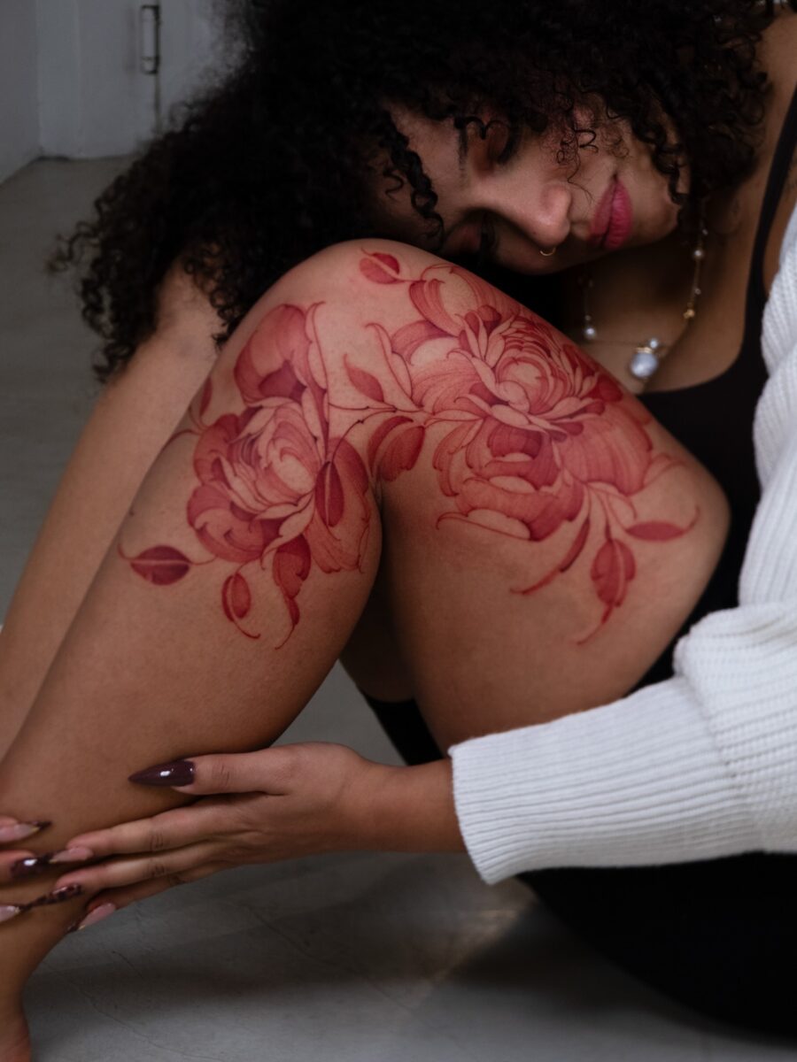 Elegant red ink roses on female thigh