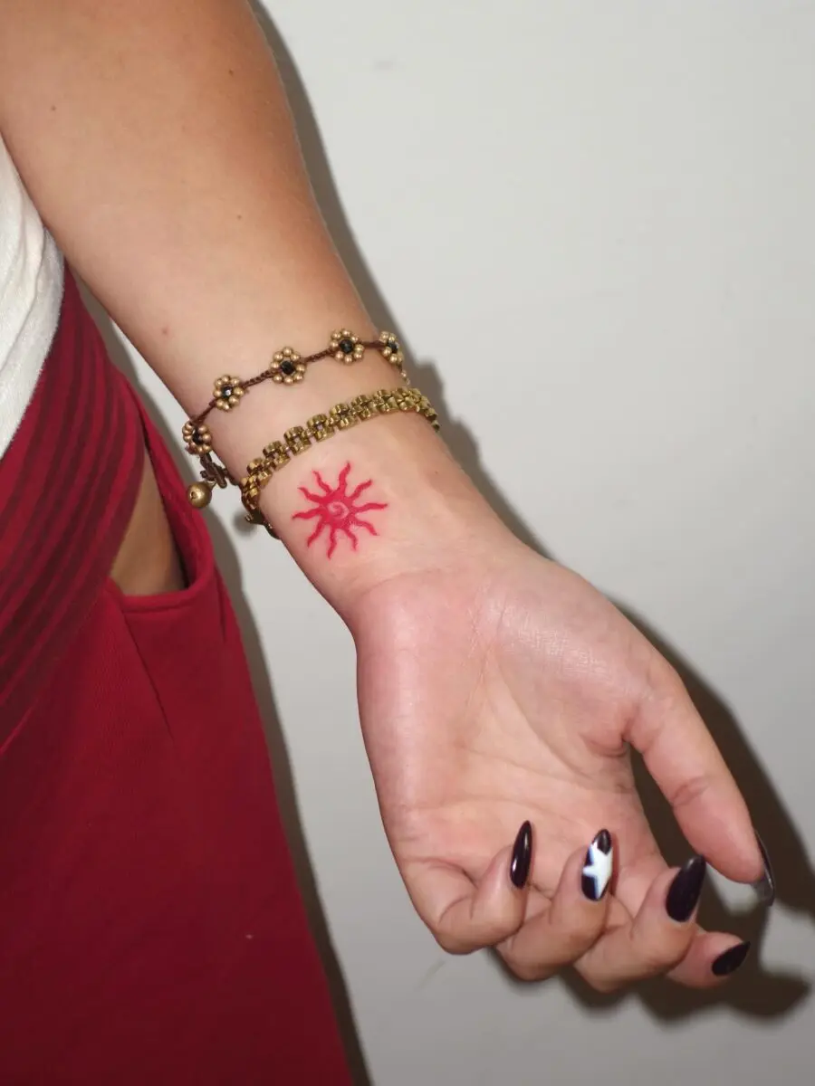 Vibrant red sun tattoo on wrist