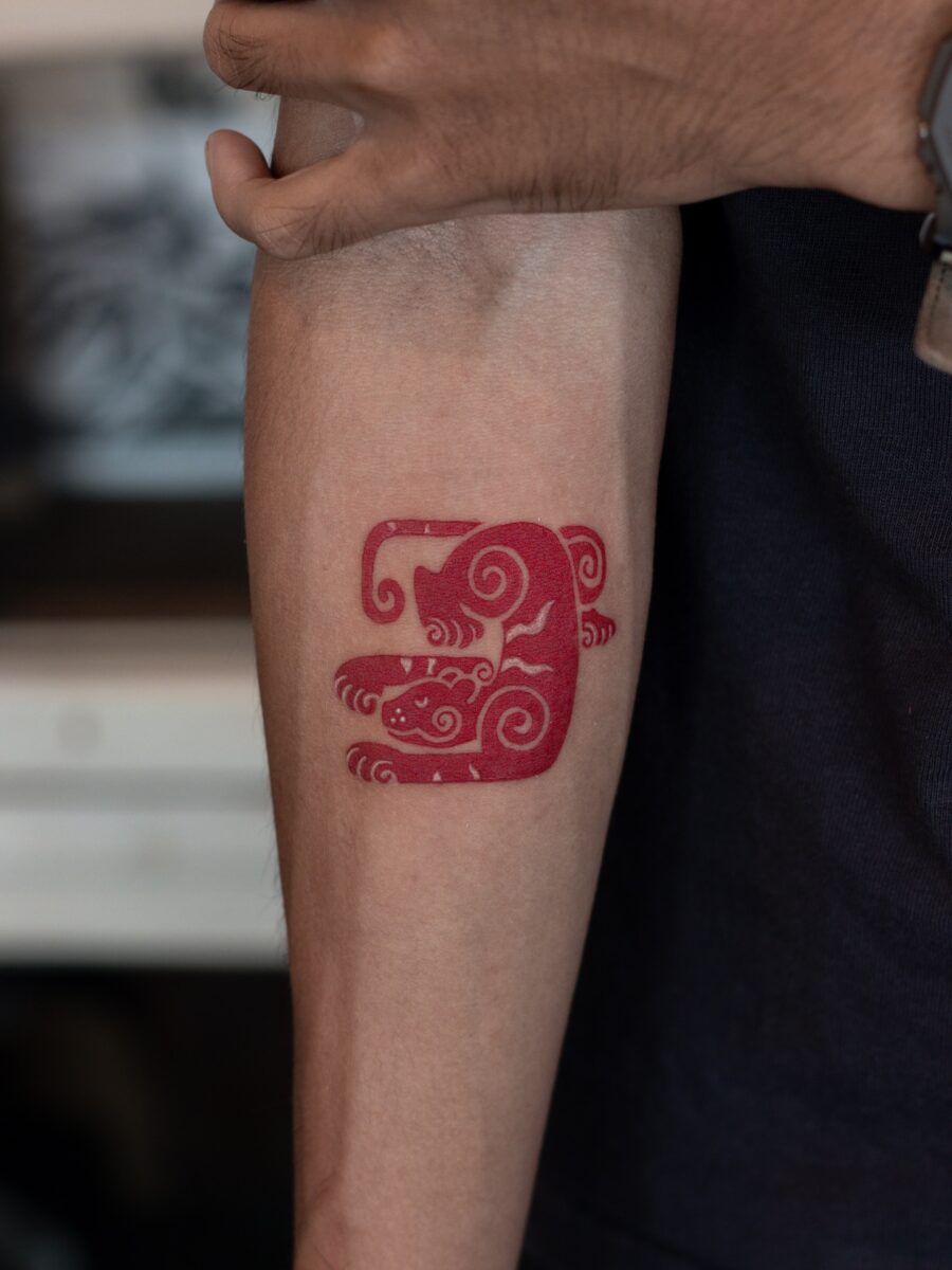 Unique red ink tattoo with swirling designs