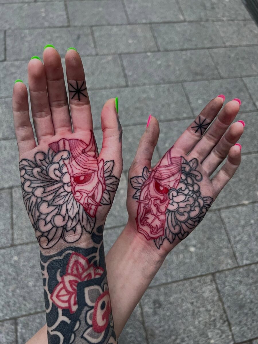 Bold red ink tattoos on intricately designed hands