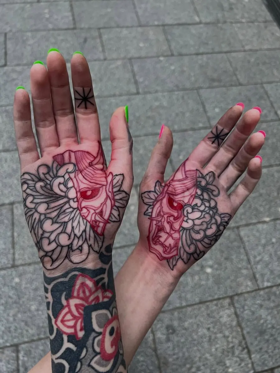 Bold red ink tattoos on intricately designed hands