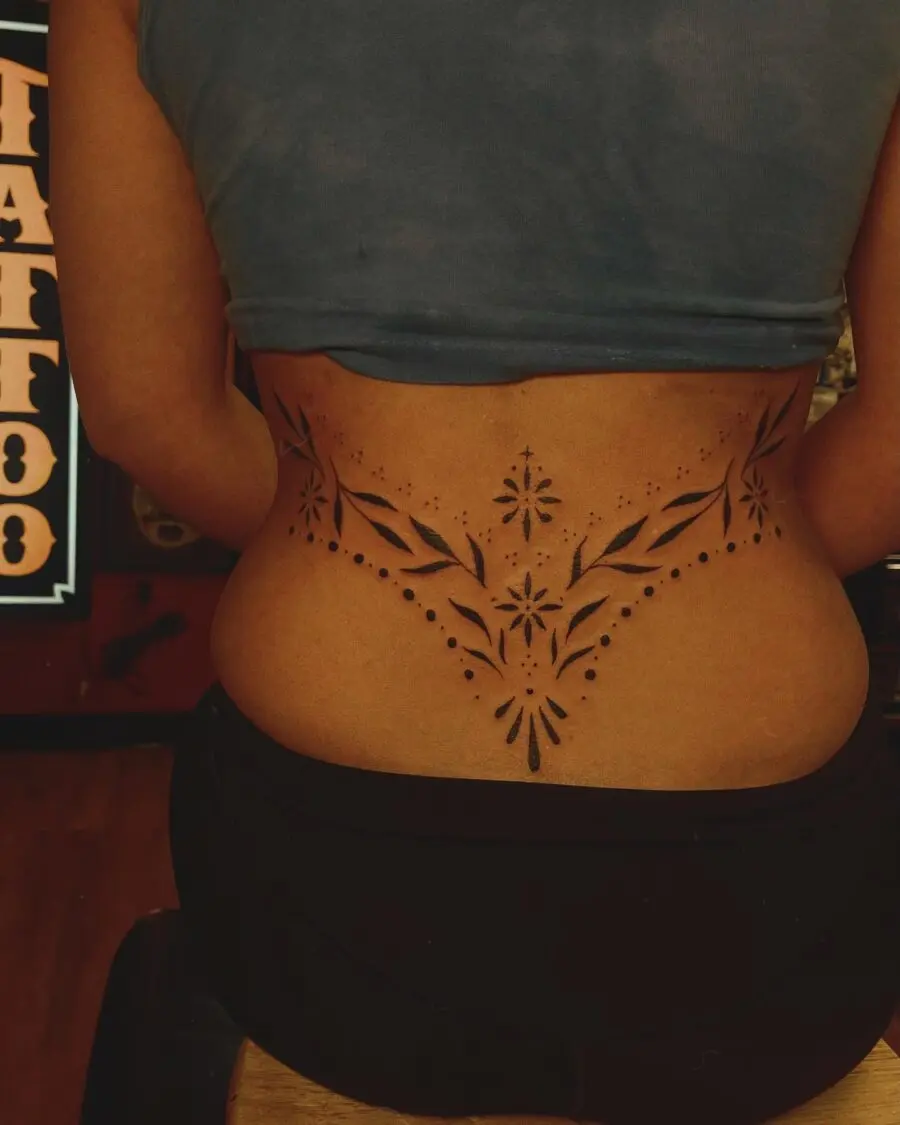 Intricate floral tramp stamp tattoo in black ink