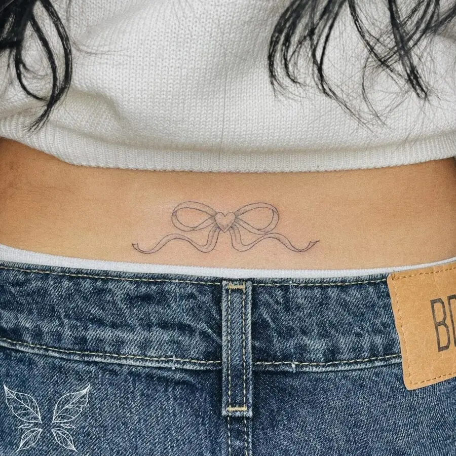 Delicate bow tattoo with a heart accent