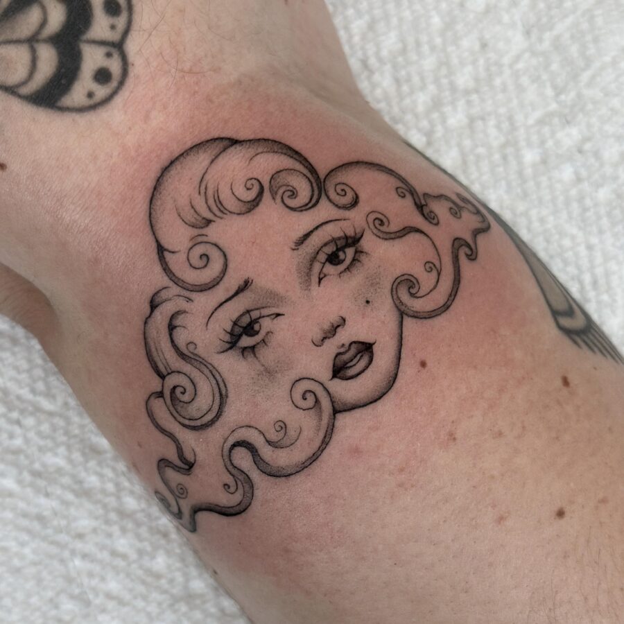 Charming whimsical face tattoo with curly hair