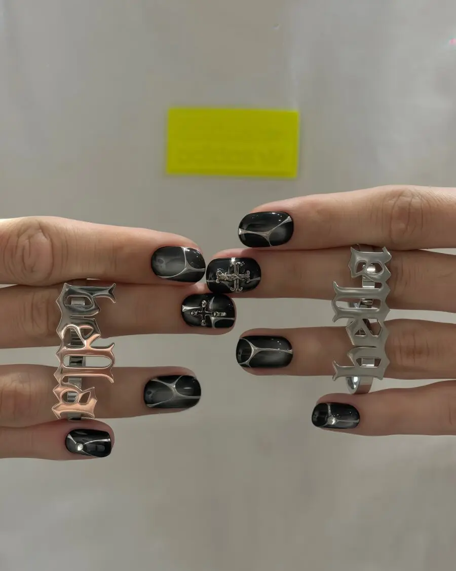 Bold black nails with metallic charm designs
