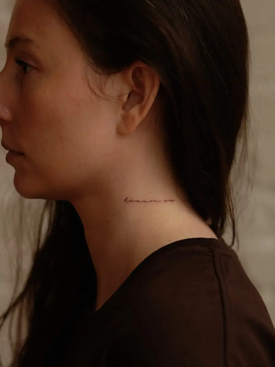 Elegant script tattoo on the neck