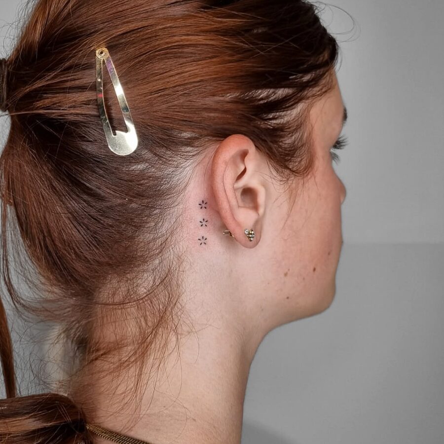 Delicate floral tattoo discreetly placed behind ear
