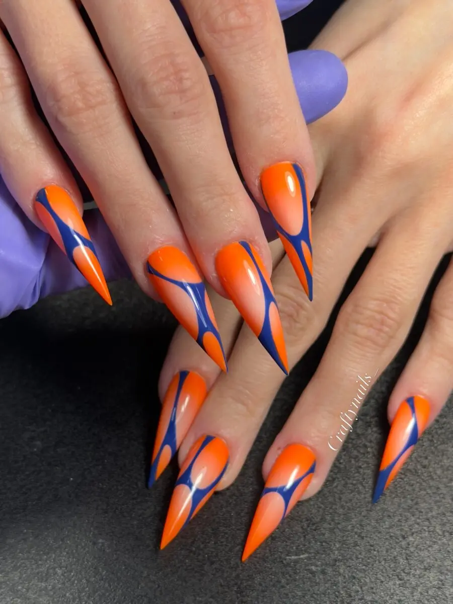 Bold stiletto nails with vibrant orange accents